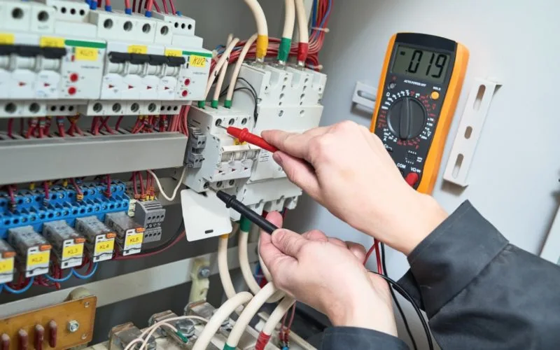 Électricien vérifiant un tableau électrique avec multimètre