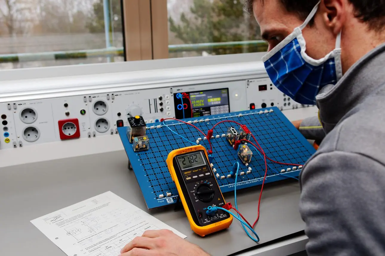 Technicien utilisant un multimètre numérique avec des équipements de protection adaptés