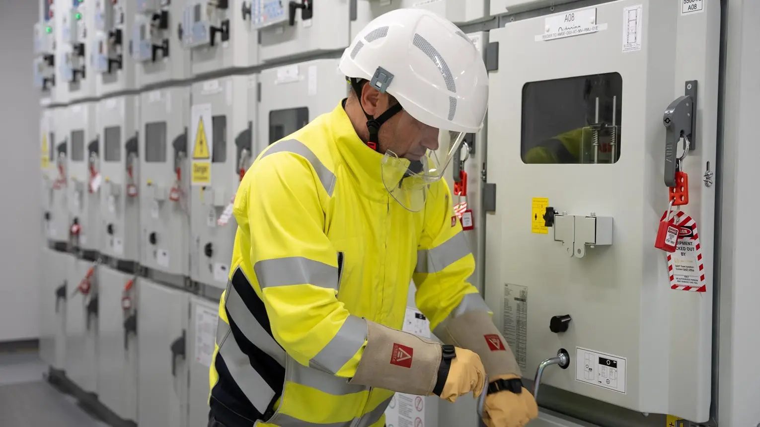 Ingénieur inspectant des équipements électriques dans un poste de transformation haute tension.